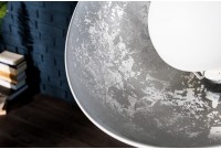 Une lampadaire trepied design en acier inoxydable et en aluminium coloris blanc et argenté